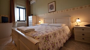 Un dormitorio ordenado con cama, mesitas de noche, cómoda y radiador.