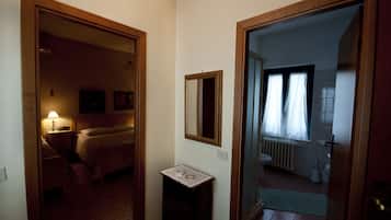 Una habitación de hotel con cama, mesita de noche, lámpara y una pequeña mesa con un objeto decorativo.