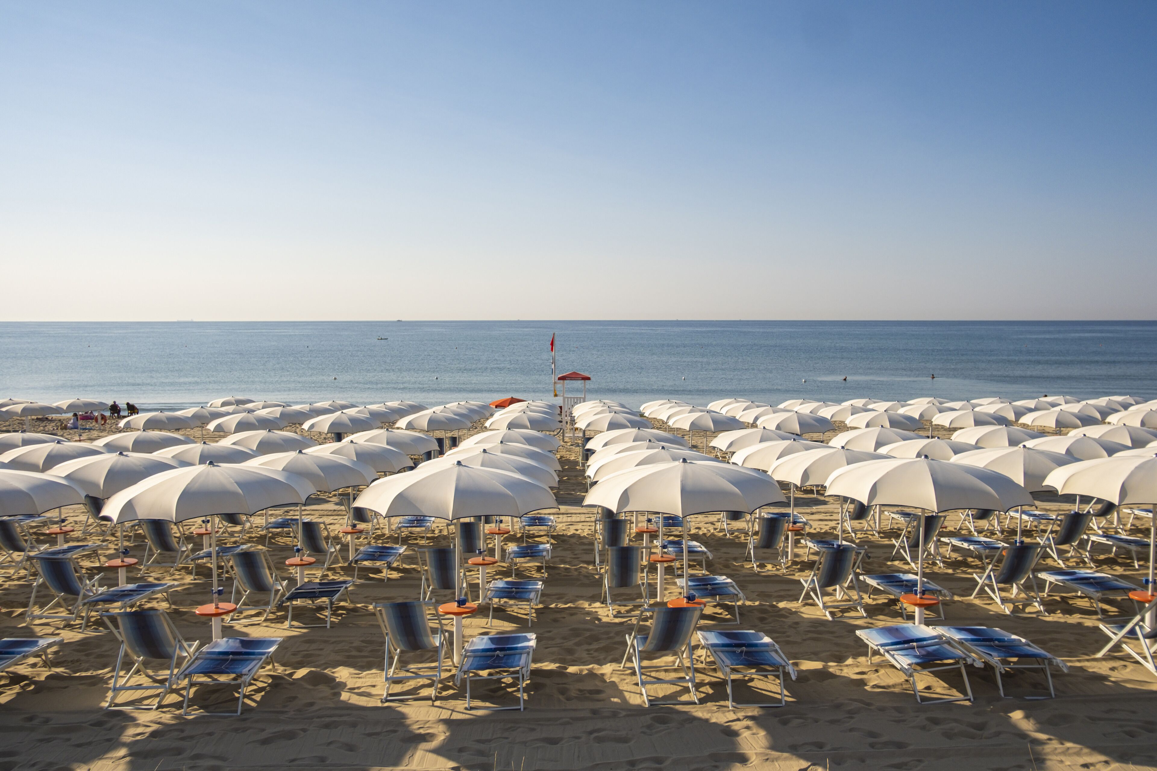 Une plage bordée de rangées de parasols et de chaises longues.