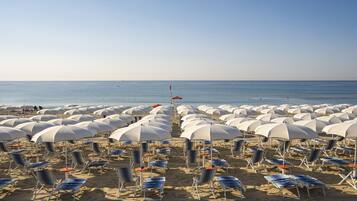 Une plage bordée de rangées de parasols et de chaises longues.