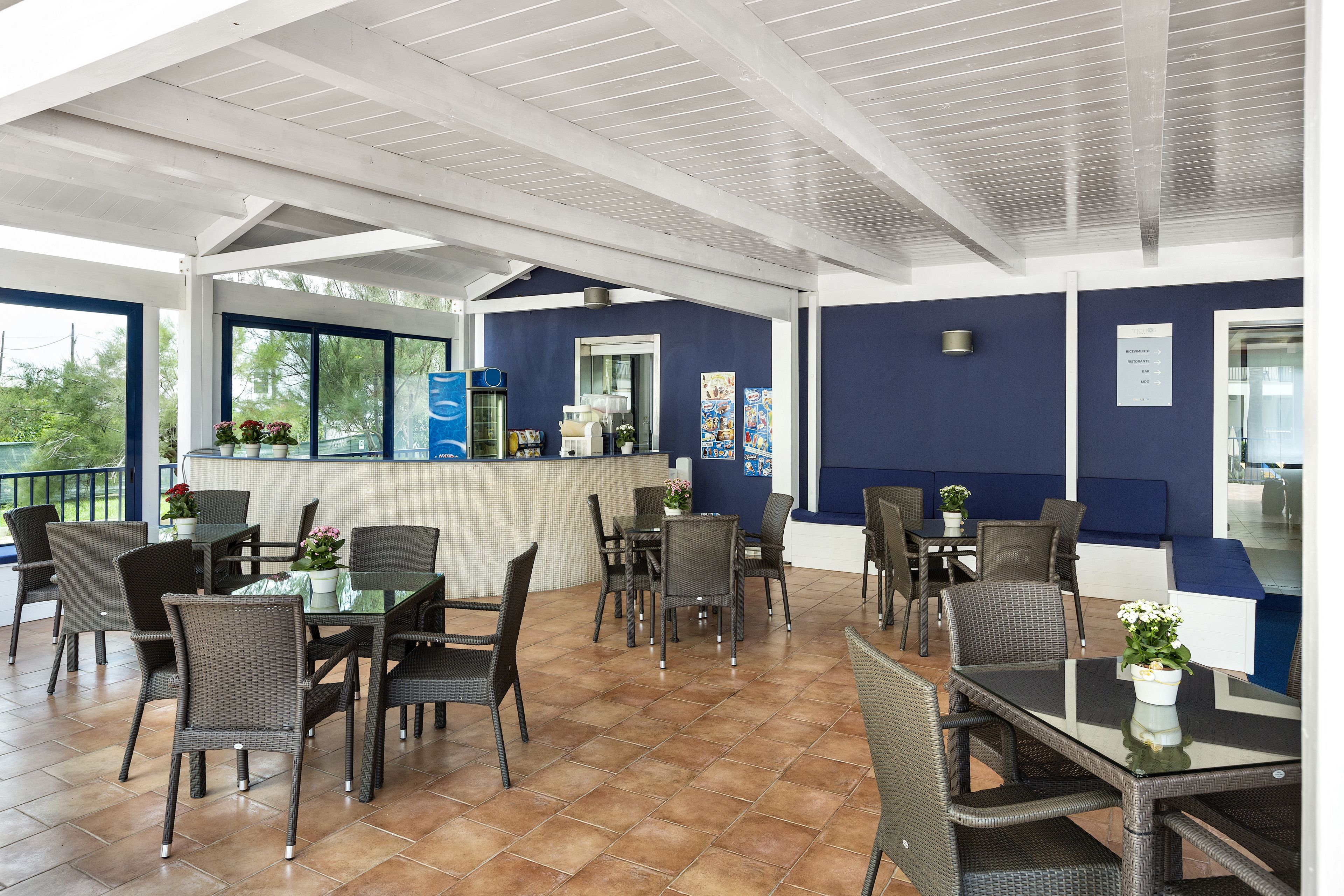 An outdoor patio area with tables and chairs, a counter with a menu, and a view of the outdoors.