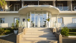 L’entrée d’un hôtel moderne, avec une façade incurvée, de grandes portes vitrées et un escalier menant à l’entrée.