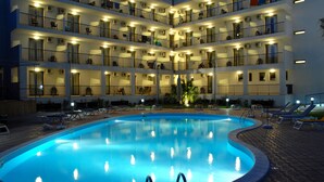 Un hôtel à plusieurs étages doté d’une piscine, de balcons et d’un espace extérieur aménagé pour s’asseoir.