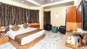 A hotel room with a large bed, a desk with a coffee maker, and a television. - Hotel Dayal (Udaipur)