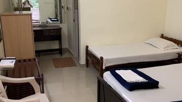 A hotel room with a bed, a desk with a laptop, a chair, and a wardrobe.