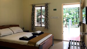 Une chambre d’hôtel avec un lit, une fenêtre avec des rideaux, un téléviseur et une porte donnant sur l’extérieur.