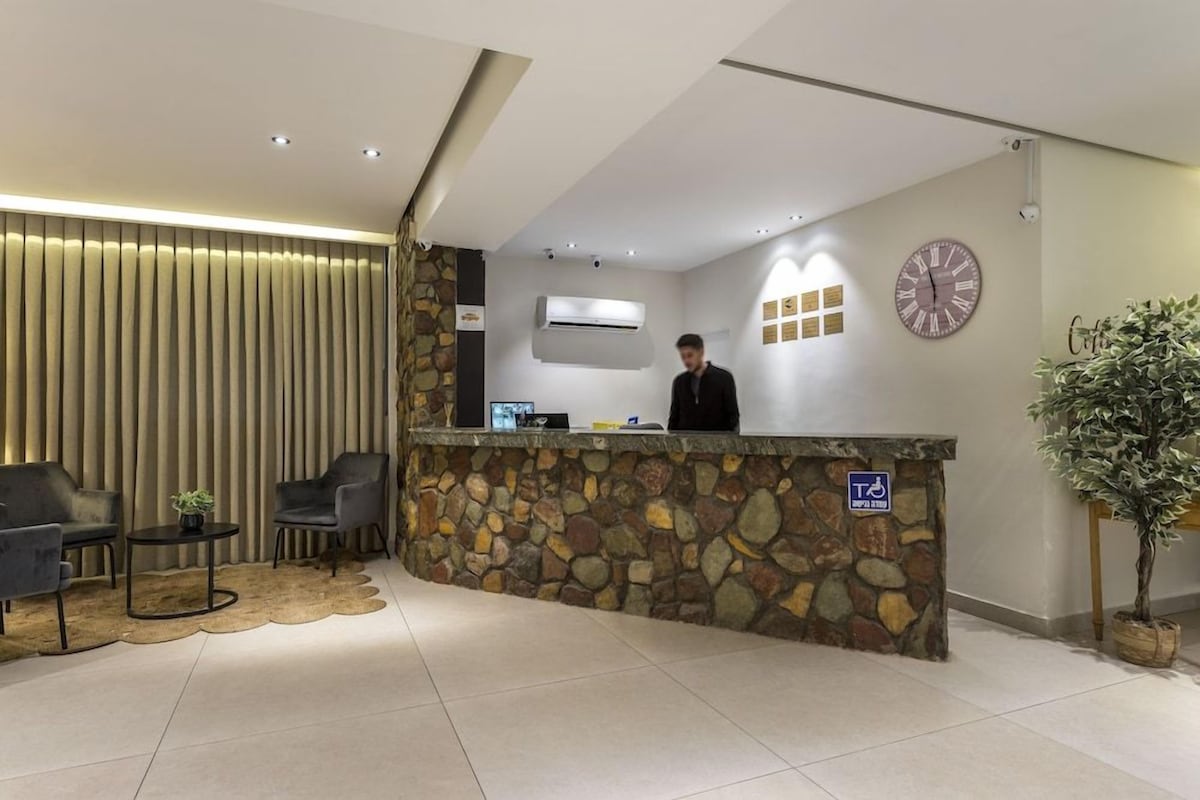 Un área de recepción con mostrador de piedra, un reloj y una mesa de recepción.