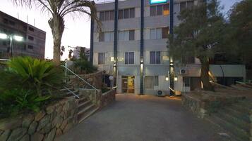 A multi-story hotel with a stone facade, multiple windows, and a flag.