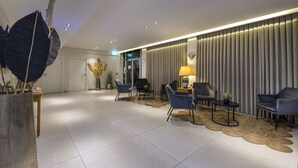 A modern lobby with a reception desk, seating area, and a large decorative plant.