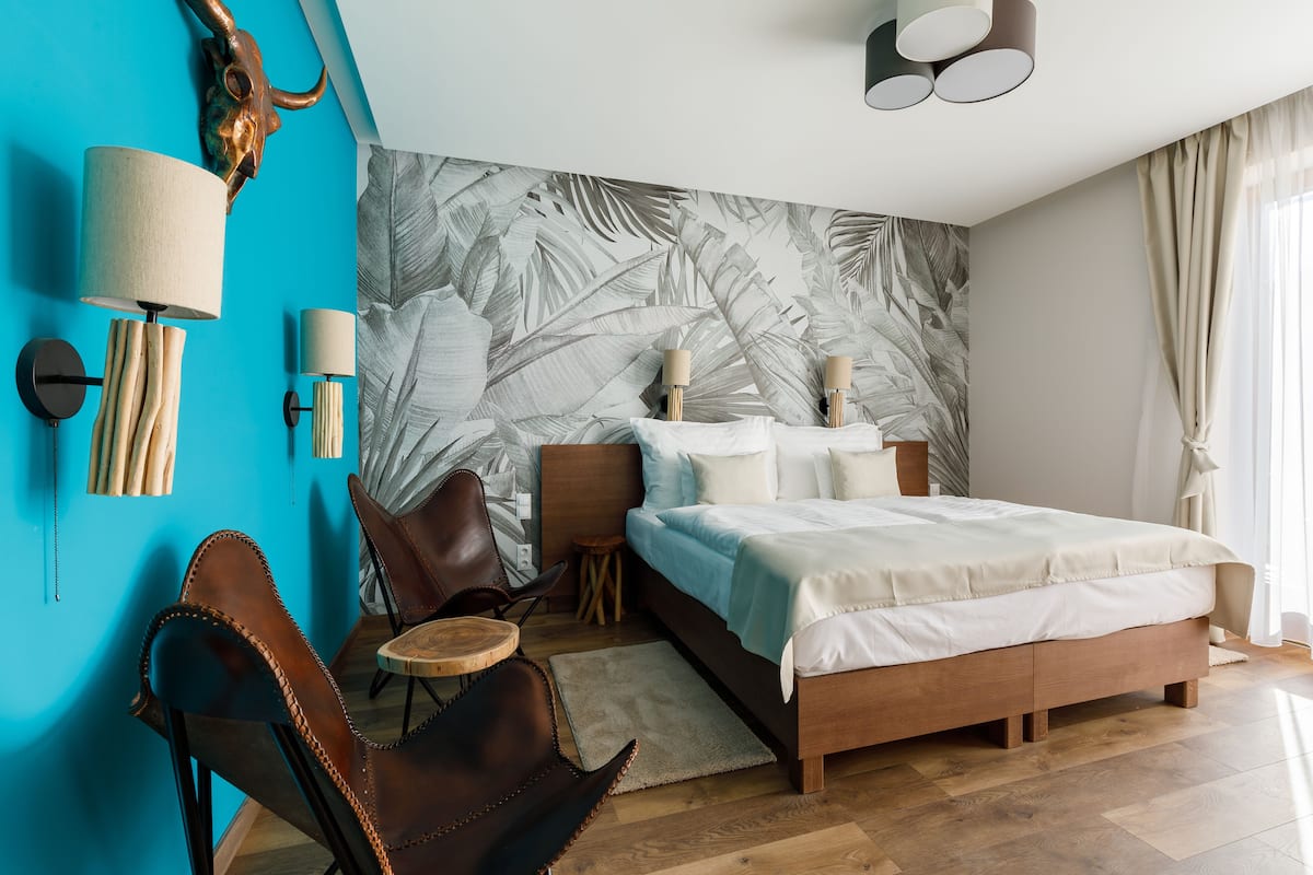 A modern bedroom with a bed, a chair, a small table, and a wall-mounted lamp.