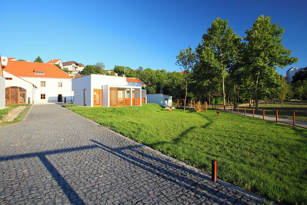A cobblestone pathway leading to a building with a white facade and orange roof.