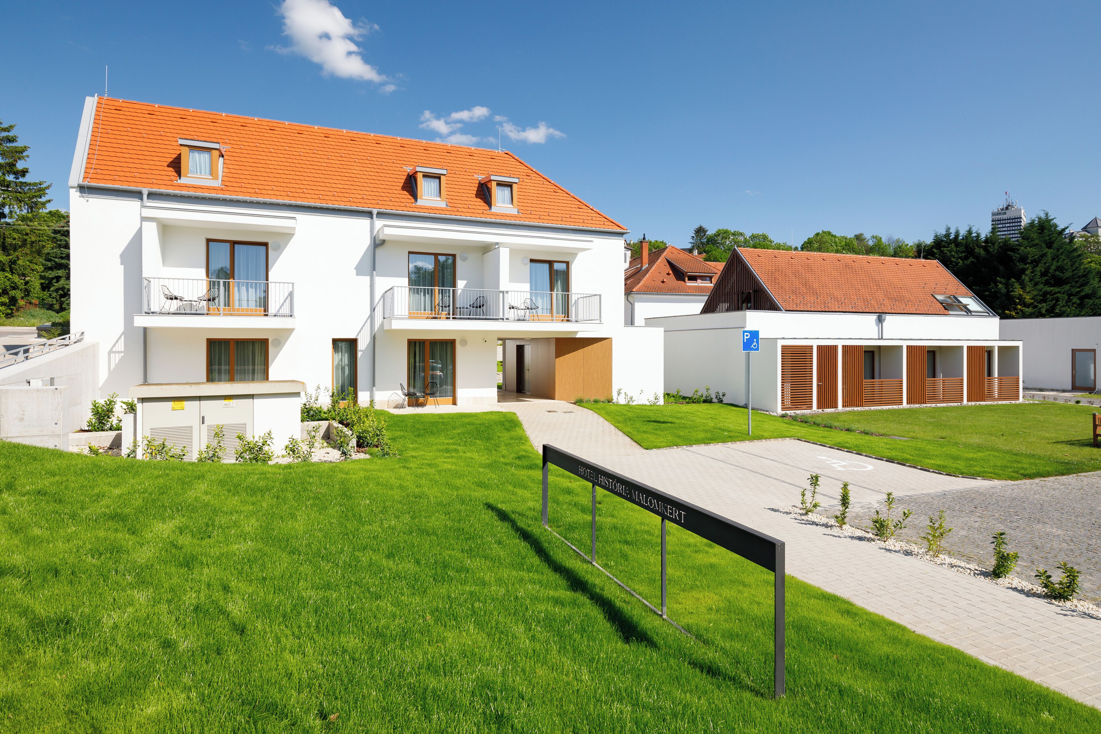 Ein modernes Hotel mit heller Fassade, mehreren Balkonen und einem gepflasterten Eingangsbereich.