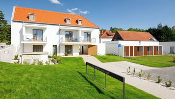 Ein modernes Hotel mit heller Fassade, mehreren Balkonen und einem gepflasterten Eingangsbereich.
