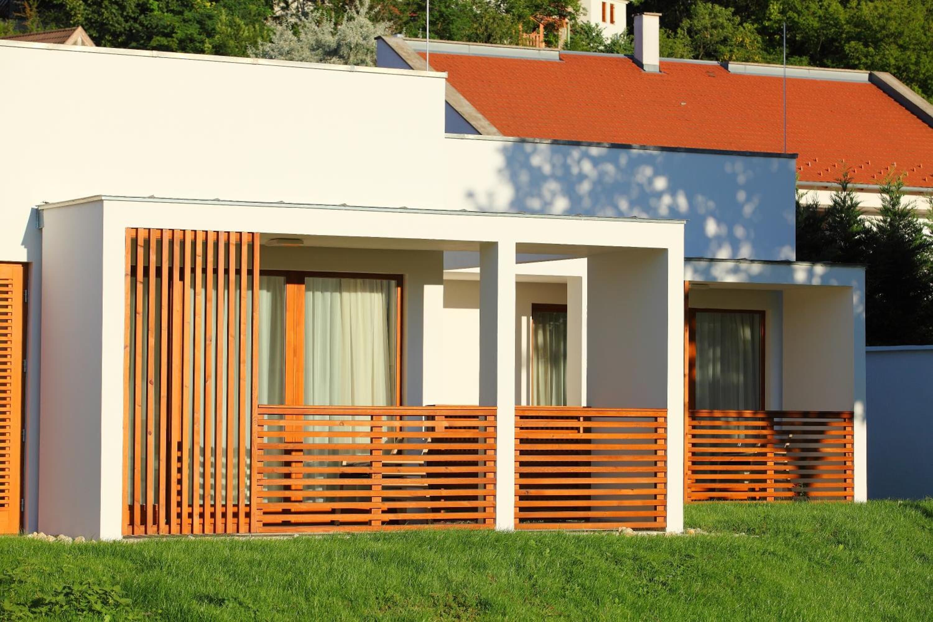 Un edificio moderno de dos pisos con techo plano, ventanas amplias y cerca de madera.