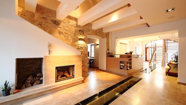Un amplio espacio de sala con chimenea de piedra, una escalera y una cocina al fondo.