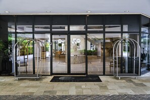 A hotel entrance with glass doors, a reception desk, and a seating area visible through the glass. - Hotel Ninety (São Paulo)
