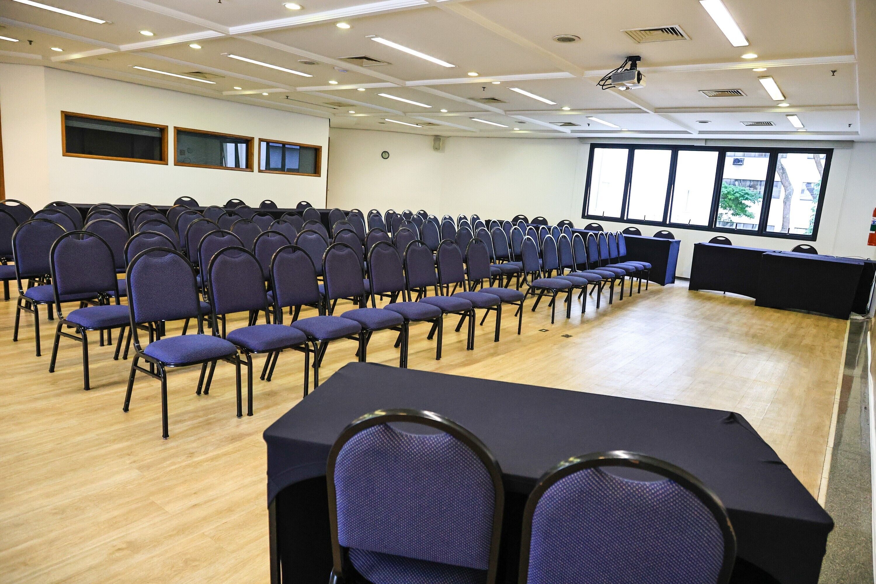 A conference room with rows of chairs, a projector, and large windows.