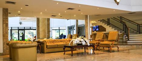 A spacious lobby with a large sofa, armchairs, a coffee table, and a decorative centerpiece.