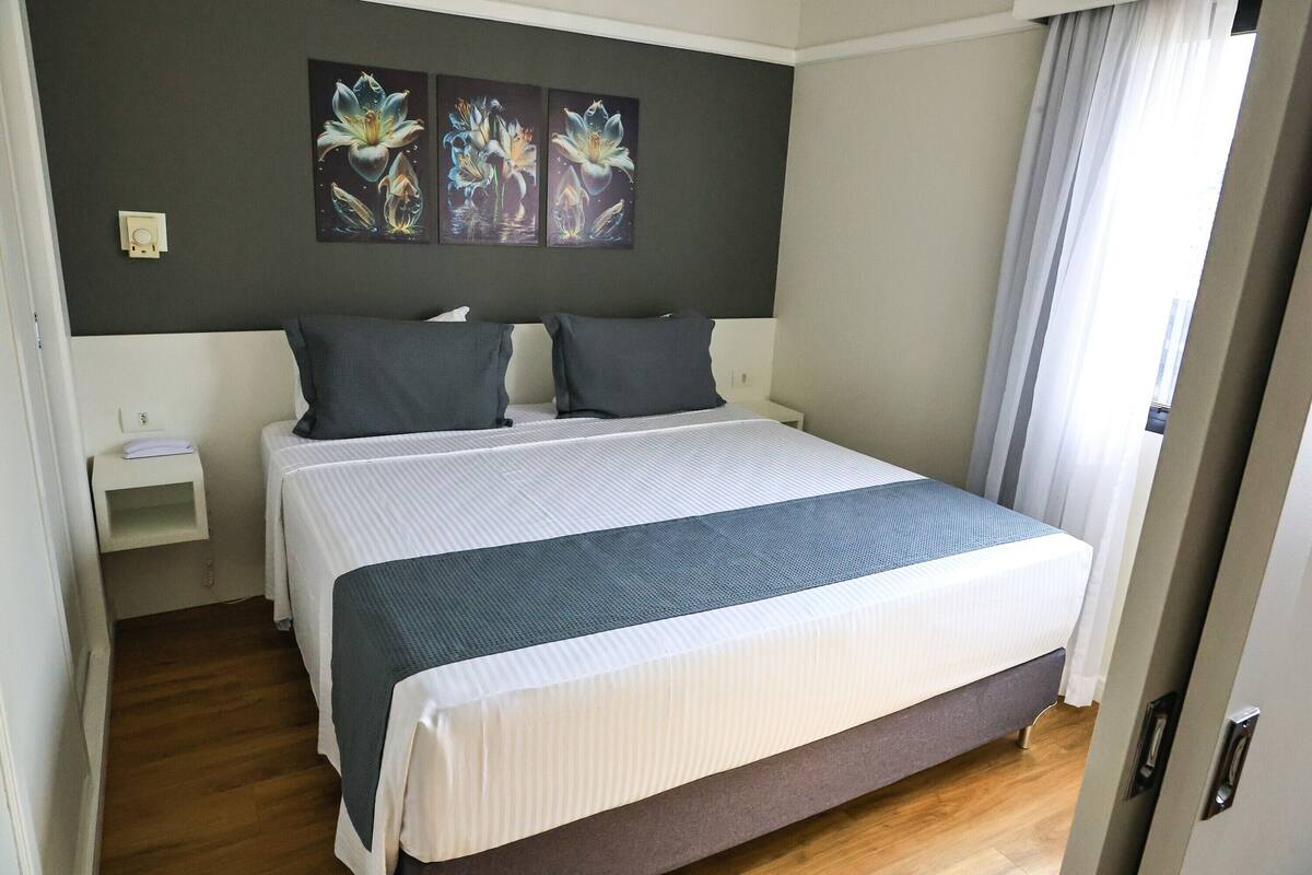 A bedroom with a large bed, two bedside tables, and a wall-mounted light.