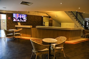 A reception area with a counter, wicker chairs, a television, and a staircase.