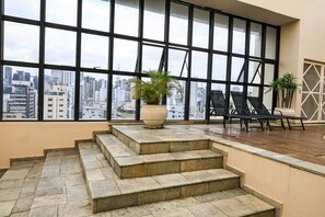 A rooftop terrace with a view of the city, stone steps, and two lounge chairs.