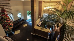 A lobby with a reception desk, a Christmas tree, a sofa, and a large plant. - Bombinhas Summer Beach Hotel & Spa (Bombinhas)
