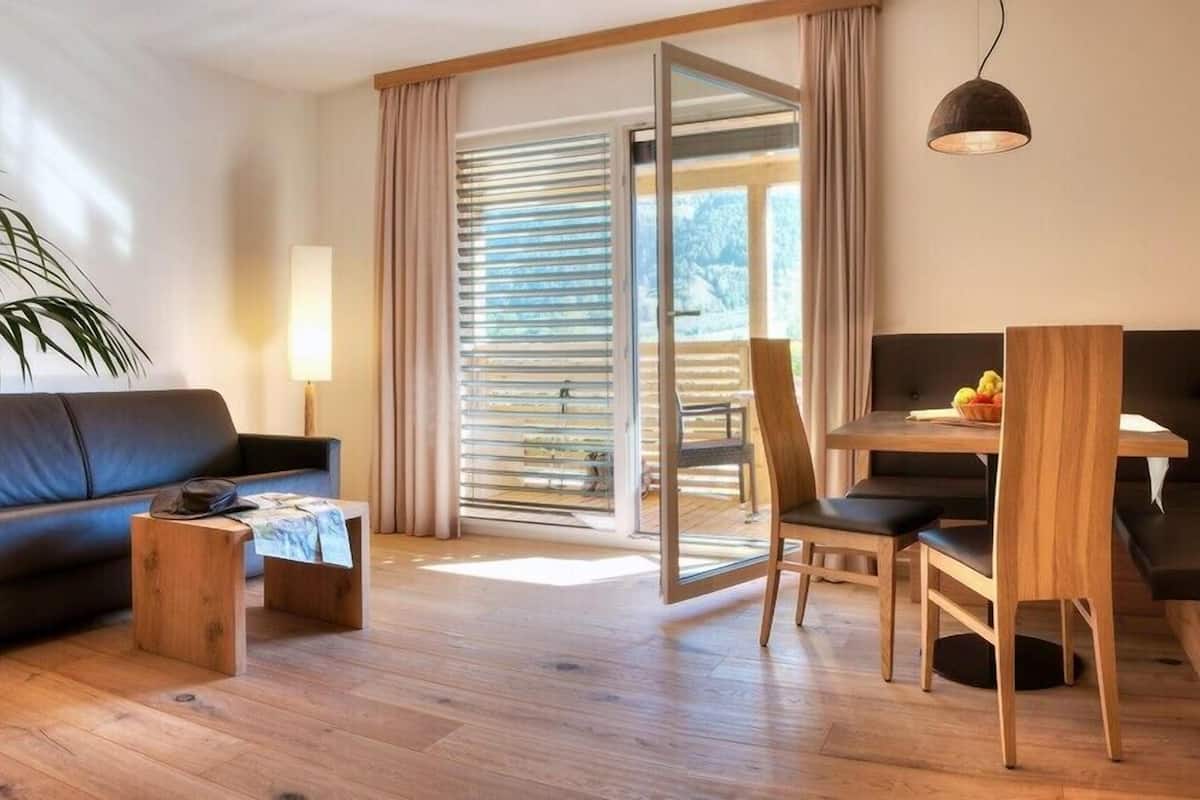 A modern living room with a sofa, coffee table, and a dining area with a table and chairs.
