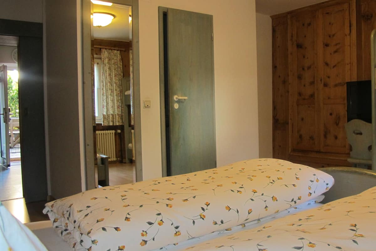 A bedroom with two single beds, a wooden wardrobe, and a bunk bed in the corner.