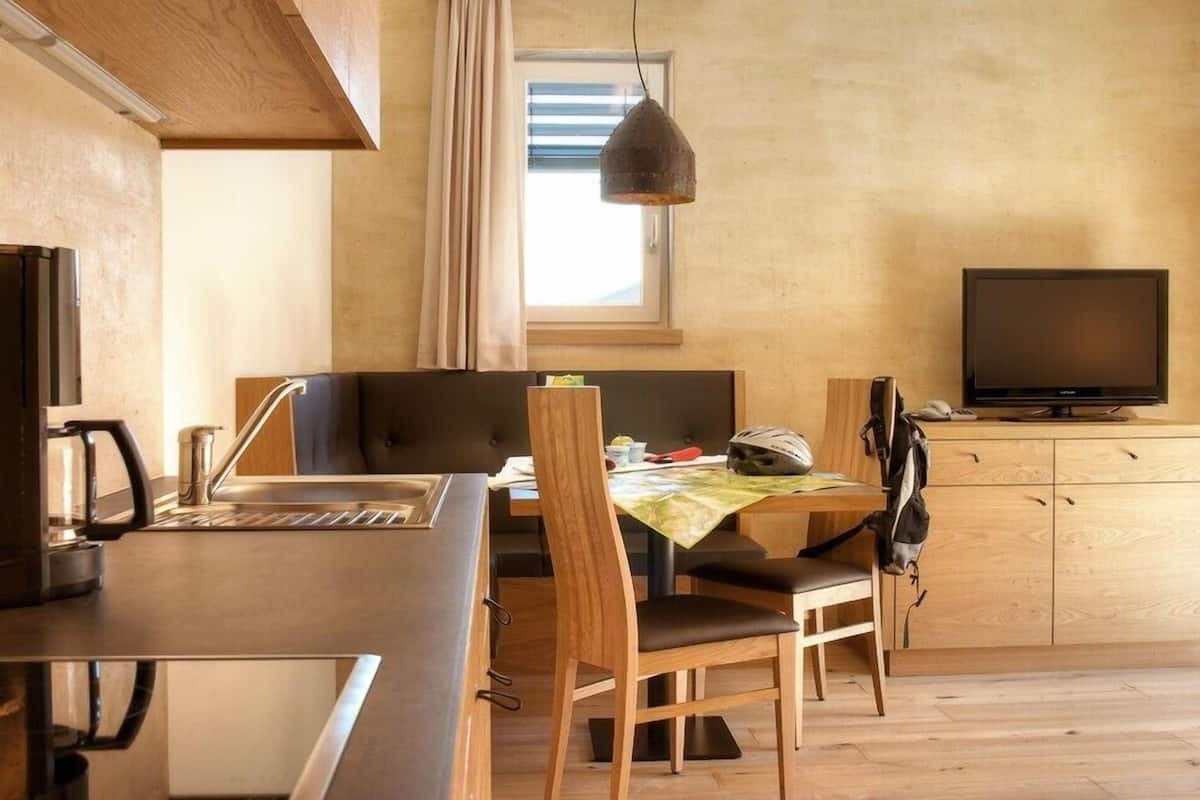 A compact kitchen with a dining area, a TV, and a window with blinds.