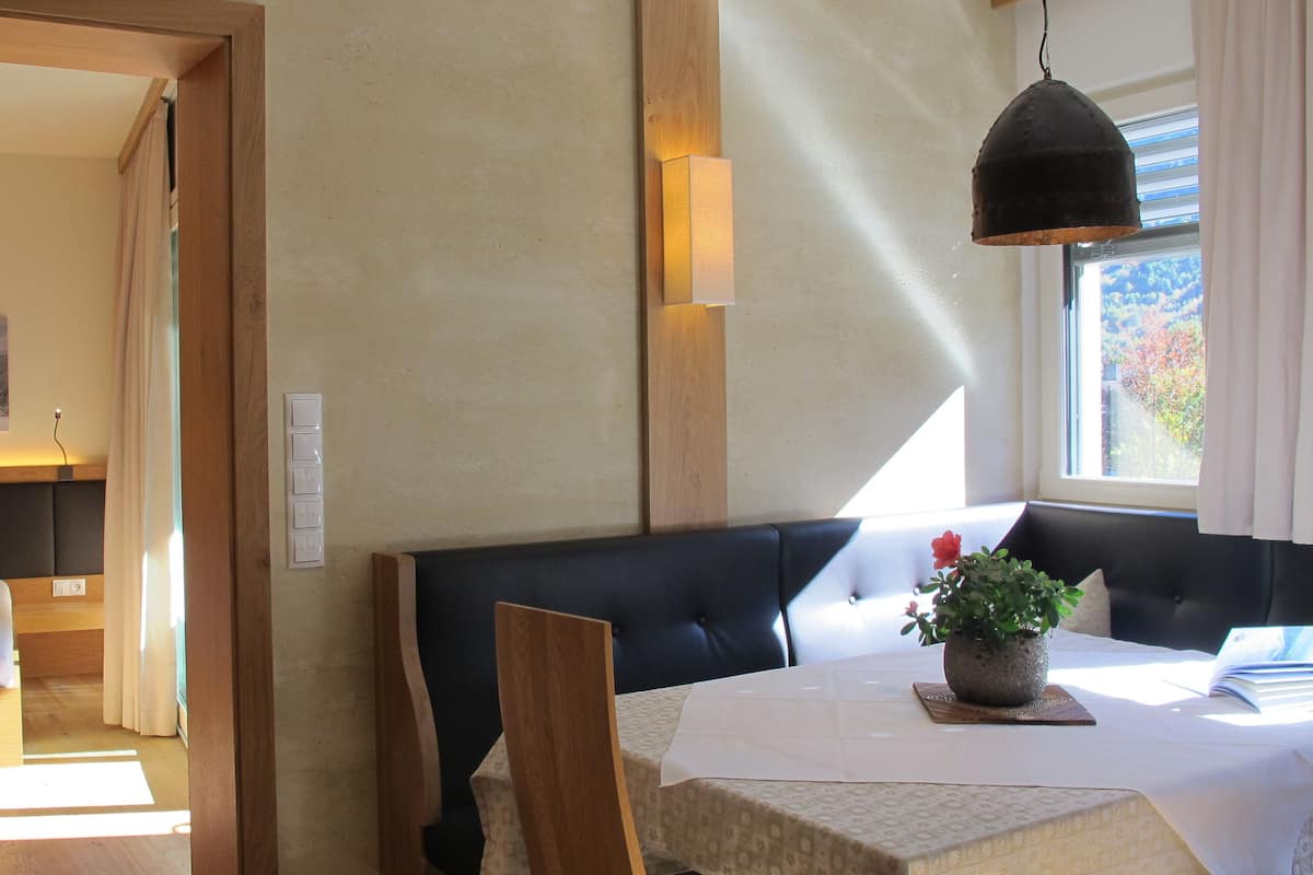 A hotel room with a bed, a seating area with a table, and a window with a view of trees.