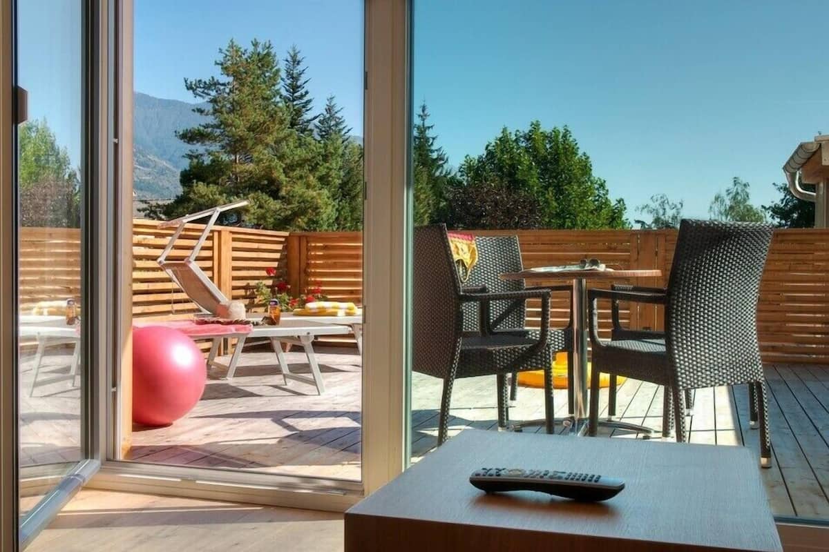 A patio with a table and chairs, a red exercise ball, and a remote control on the table.