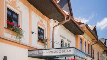 Un hotel con un letrero que dice "HOTEL HVIEZDOSLAV" y macetas con flores en las ventanas.