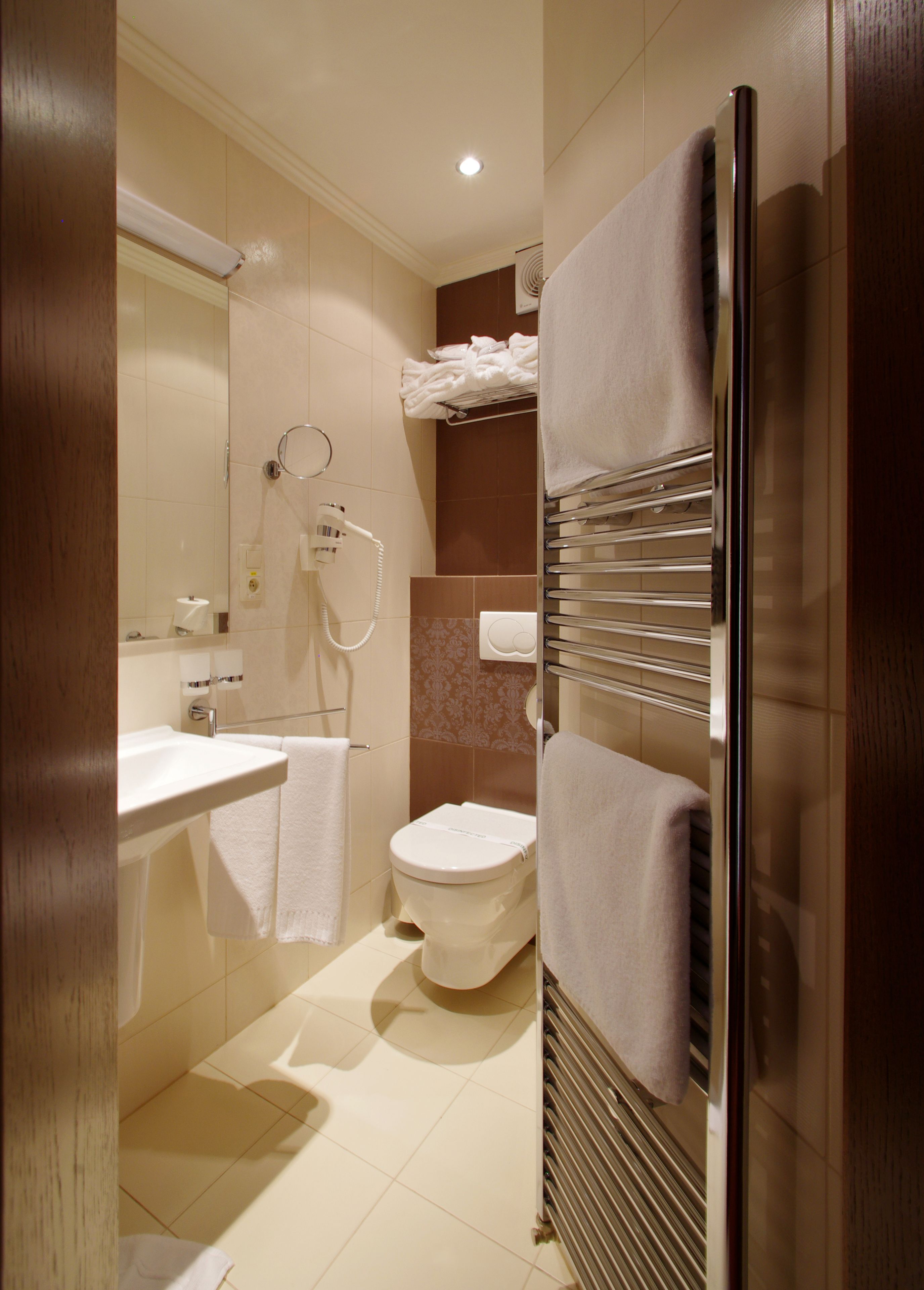 Un baño moderno con lavamanos, inodoro y perchero para toallas.