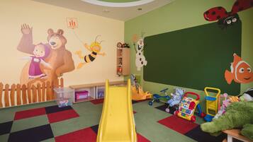 Children can play and learn in this vibrant playroom with a slide, toys, and a chalkboard.