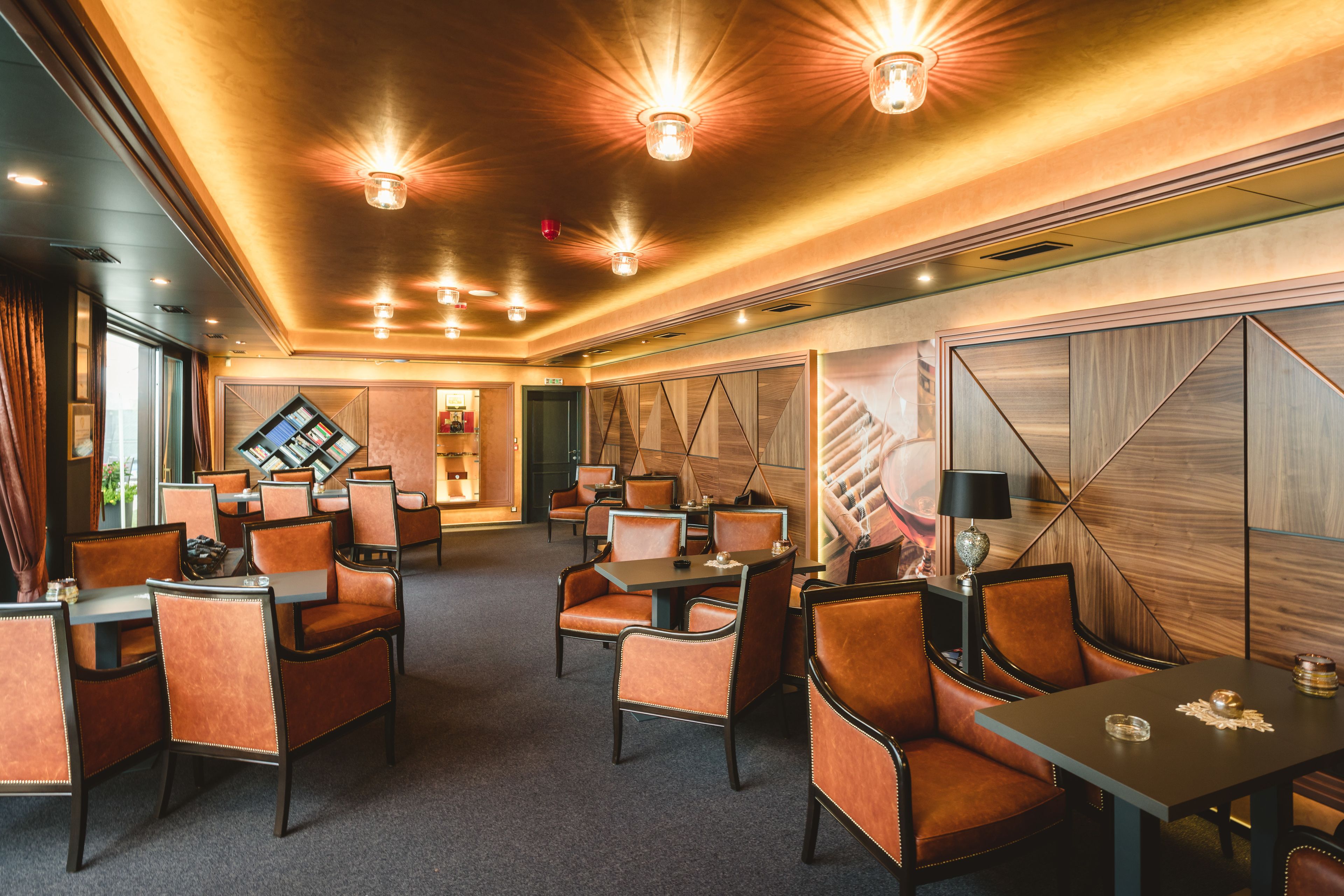 A modern hotel lobby with leather seating, a digital display, and warm lighting.