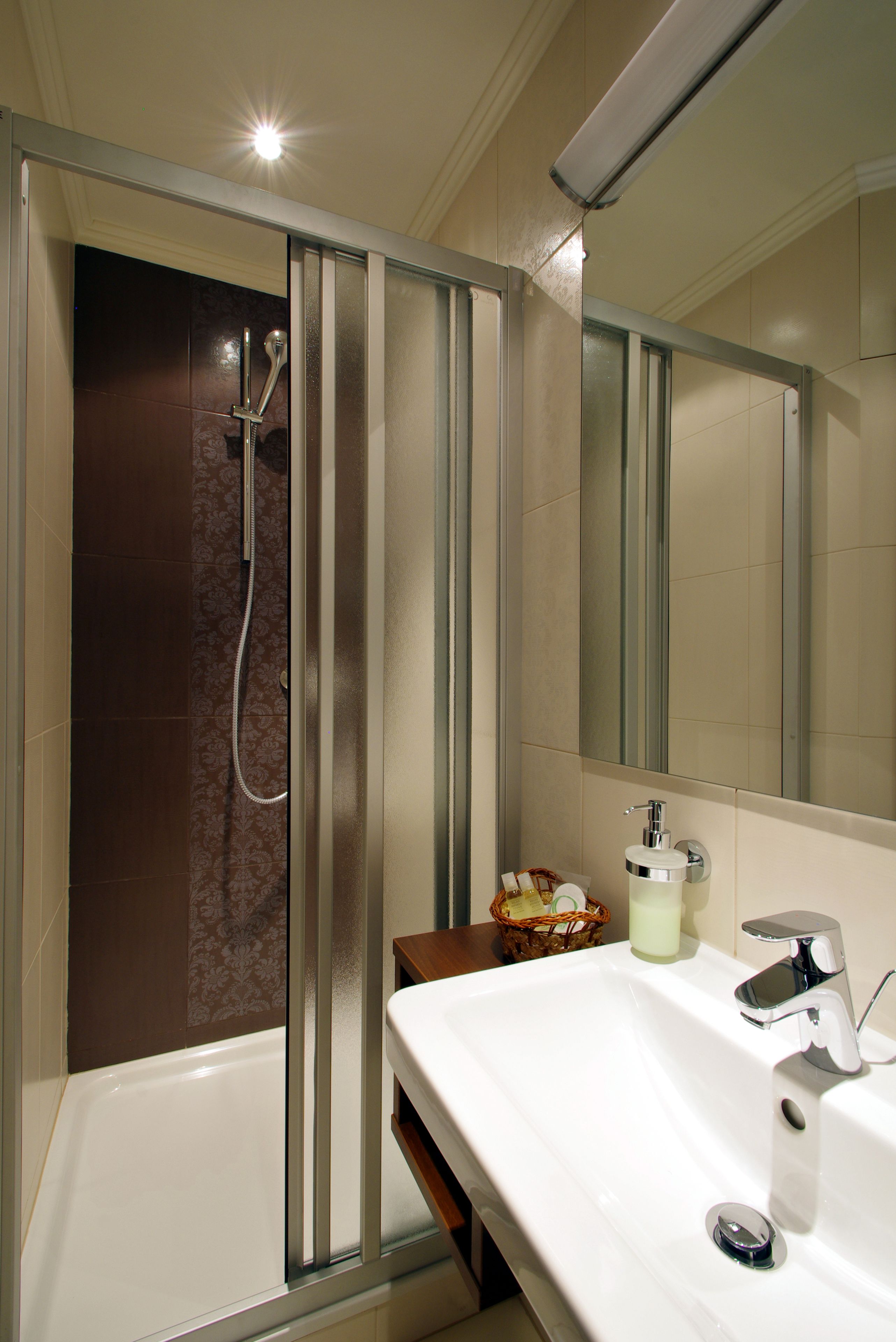 Un baño moderno con ducha envuelta en vidrio, un lavabo blanco y un espejo.