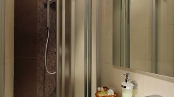 Un baño moderno con ducha envuelta en vidrio, un lavabo blanco y un espejo.