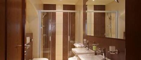 A modern bathroom with two sinks, a shower, and a toilet.