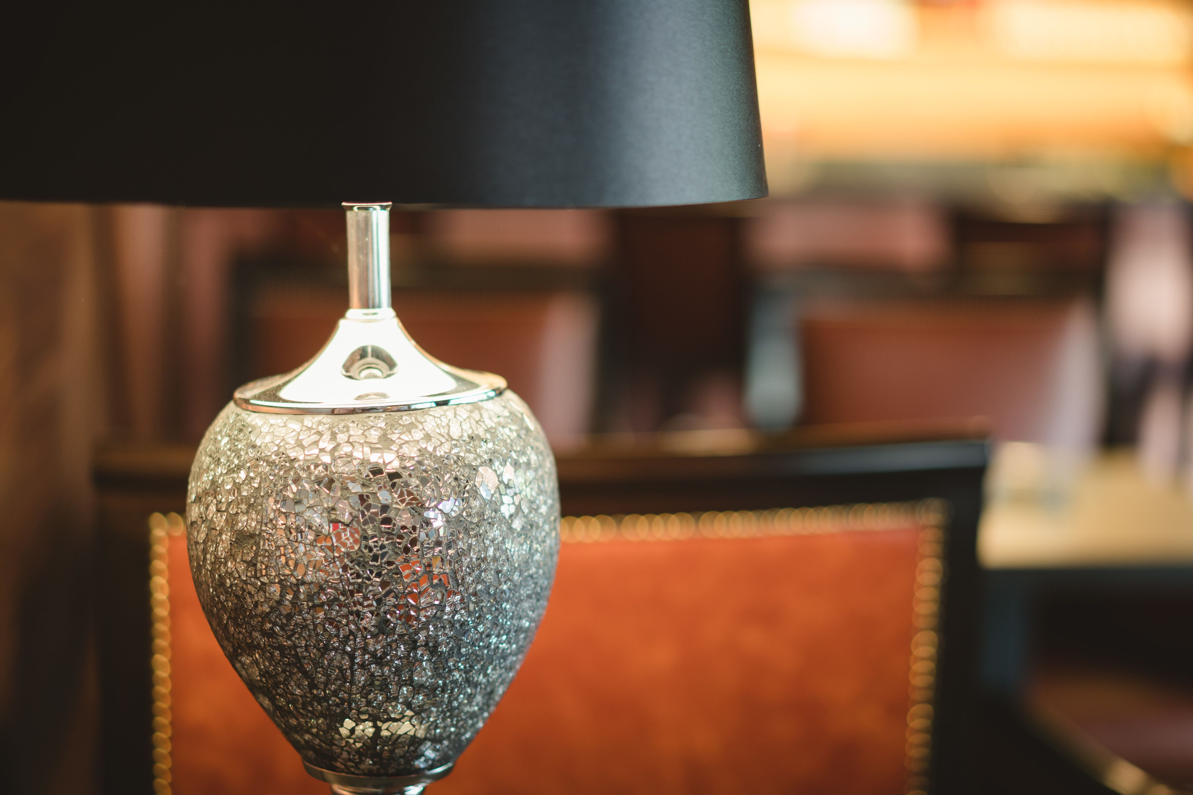 A close-up of a decorative lamp with a textured glass base and a black shade.