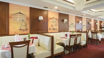 Un restaurante con cabinas y mesas, paneles de madera y murales en las paredes.