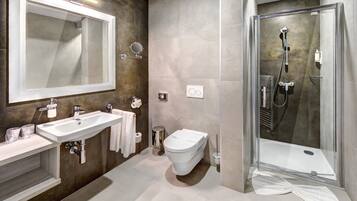 Une salle de bain moderne avec un grand miroir, deux lavabos, des toilettes et une douche à parois de verre.