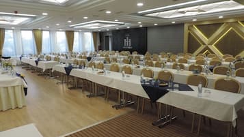 Ein Konferenzraum mit mehreren Tischen, Stühlen und einer Bühne.