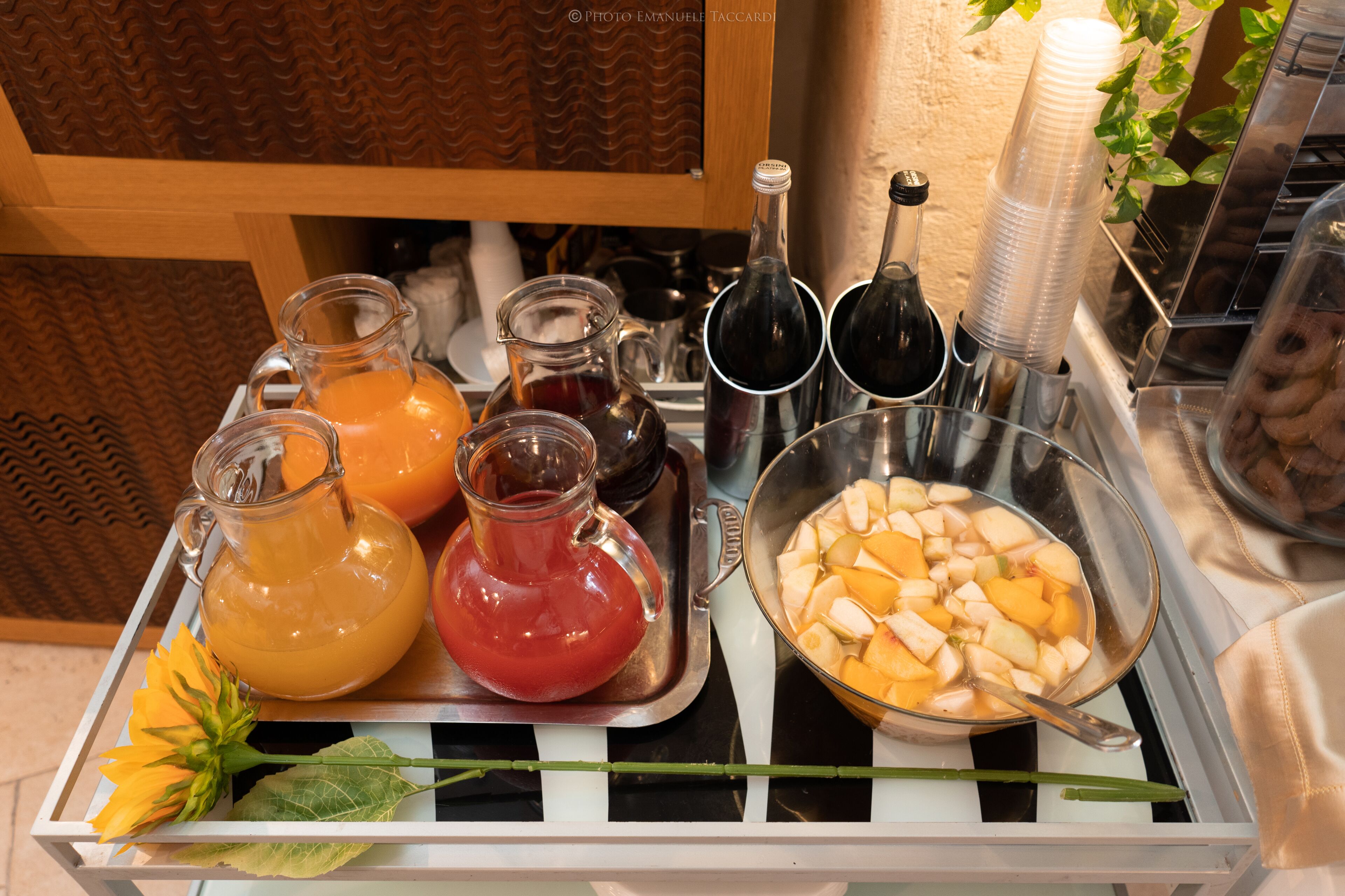 A tray with various beverages and a bowl of fruit.