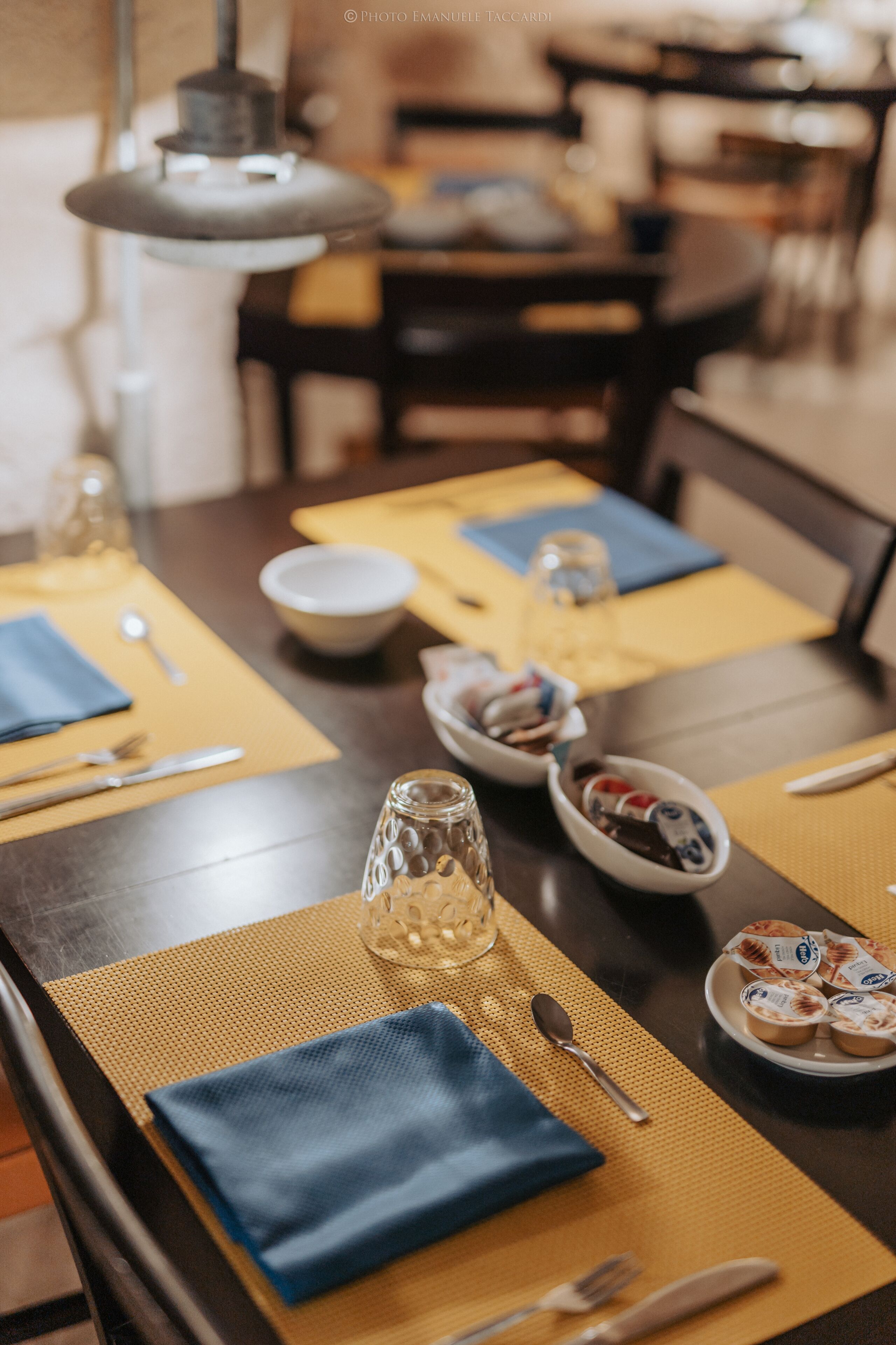 A dining table set with a bowl of fruit, a glass, and a plate of yogurt parfaits.
