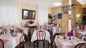A dining area with multiple tables set for service, featuring white tablecloths and pink candles. - Hotel Solemare (Jesolo)