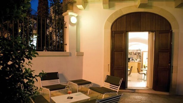 Un espace extérieur aménagé avec une table et des chaises, un pot de fleurs et une porte donnant accès à un espace intérieur.