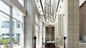 A spacious lobby with a modern design, featuring a long reception desk, comfortable seating area, and large windows providing views of the outdoor area. - Langham Place Xiamen (Xiamen)