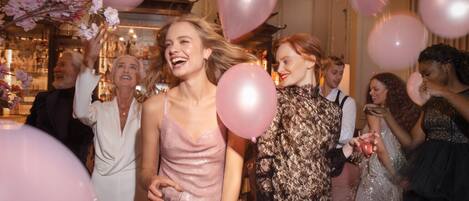 Un grupo de personas en un evento social con globos rosas y decoración floral.