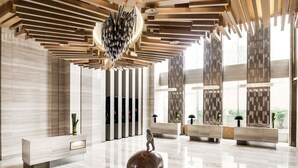 A modern lobby with a polished marble floor, a large abstract sculpture, and a unique ceiling design. - Langham Place Xiamen (Xiamen)
