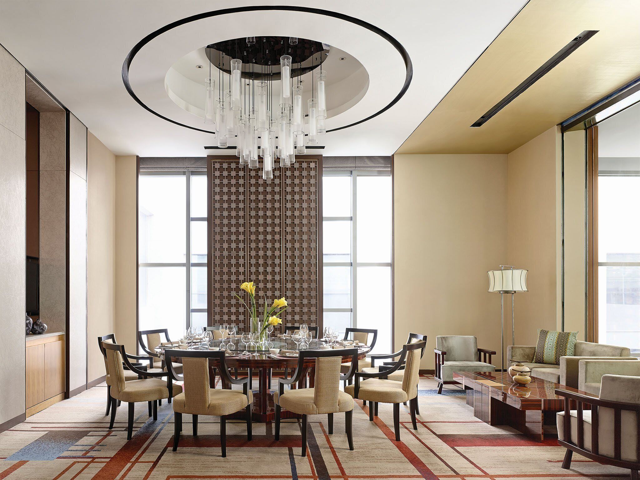 A spacious dining area with a round table, chairs, and a chandelier.